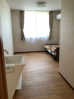 緊急コール付きの介護用ベッドが置いてある居室。窓の外に景色が見えている様子