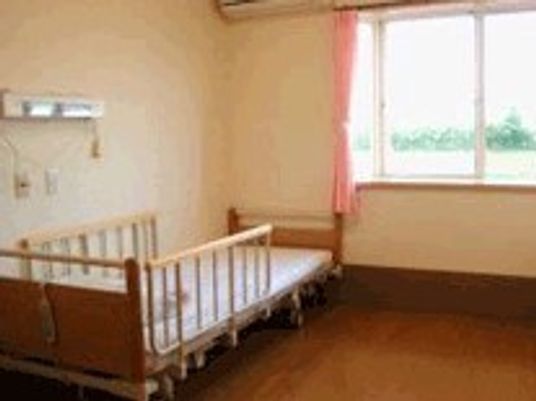 緊急コール付きの介護用ベッドが置いてある居室。窓の外に景色が見えている様子