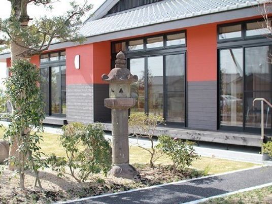 赤色が印象的な和風の建物と日本庭園風の中庭。広めの敷地がある