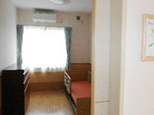 介護ベッドやタンス、レースカーテンとカーテンが付いた部屋にはエアコンもついている。