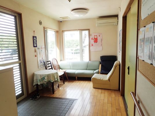 玄関には段差がなく、玄関横のロビーにはソファやいす、丸テーブルが置かれ、エアコンが付き、季節の装飾が施されている。