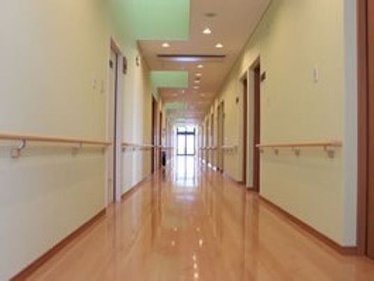 まっすぐに続いている廊下と手すりが配置してある様子。両側に個室が並んでいる