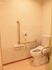 L字型の手すりと緊急コールがあるトイレ。高齢者が使う安全装置付きのトイレの写真