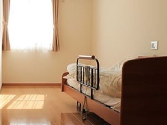 個室内にベッドがお言えてある様子。ベッドのすぐそばに緊急コールが取り付けてあるのが分かる