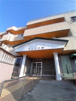 玄関の屋根部分には施設名が書かれ、3階建ての建物の各フロアにベランダが付き、屋上もある。