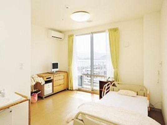 居室内を写した写真。ベッドやタンス、テレビ、エアコンなどの設備が整っている