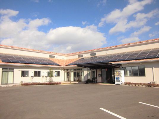 広い駐車スペースがあり、平屋建ての大きな建物はオレンジ色の屋根が付き家庭的な雰囲気。
