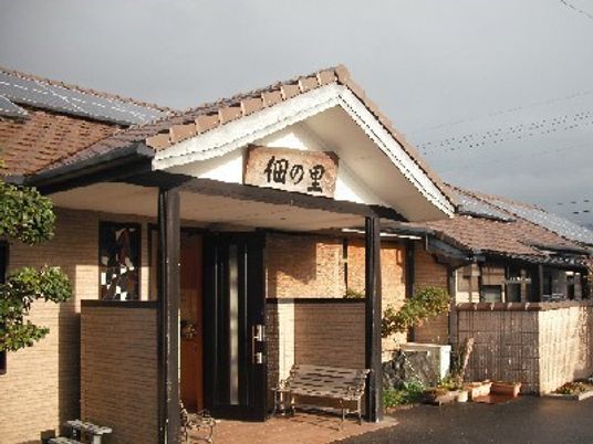 瓦屋根の平屋建ての建物は一般の家庭のような雰囲気。玄関先にはベンチがある。