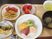 ハムエッグに魚のピカタ、イチゴ、野菜炒めとカットトマトなどが並んでいる。汁物とお茶もある。