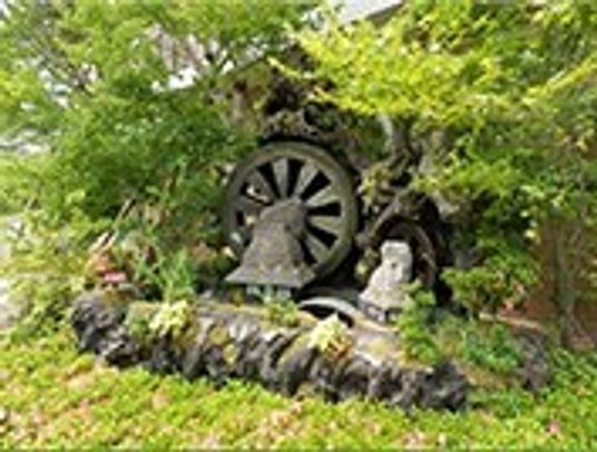 中庭に設置してある小さな水車の写真。草花に囲まれている様子