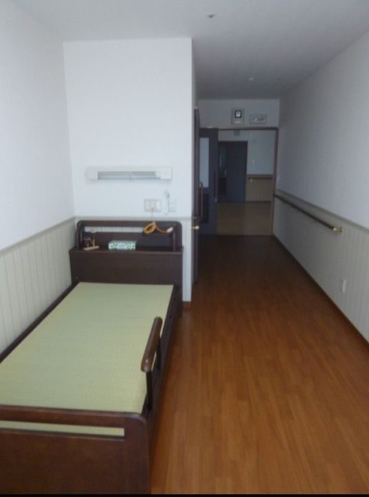 介護ベッドが置かれたフローリングの部屋には手すりが付き、ベッドサイドには緊急通報装置がある。