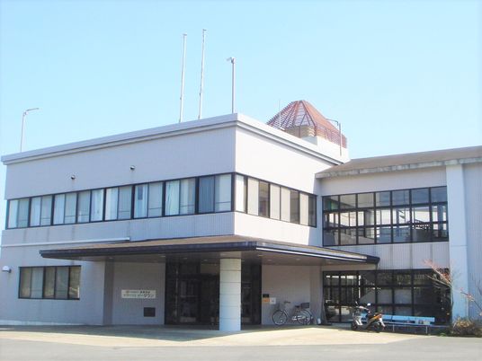 2階建ての建物は白を基調としていて玄関には車寄せが付き、建物の上の部分には赤い塔のようなものがある。