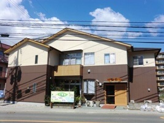 白とブラウンの２階建ての建物は日当たりのいい場所に建っている。玄関には大きな表札がある。
