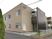 ブラウン系の２階建ての建物。白いフェンスや屋外階段もある。