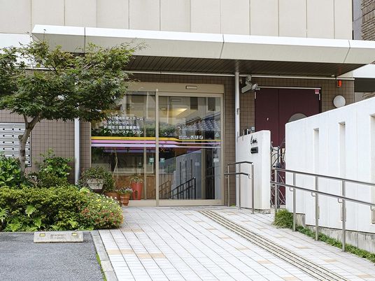 自動ドアにはたくさんの事業所名が書かれていて、エントランスに続くアプローチには手すりがある。