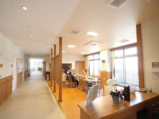まっすぐな廊下には手すりが付き、共有スペースのテーブルではスタッフと入居者が話している。