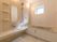 手すりや呼び出しボタンが設置された一人用の浴槽が置かれた浴室。壁には棚や鏡、シャワーも付いている。