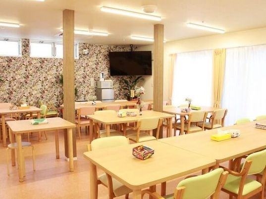 木のぬくもりあふれる空間に長机と椅子が並んでいる様子。施設内のリビングルーム