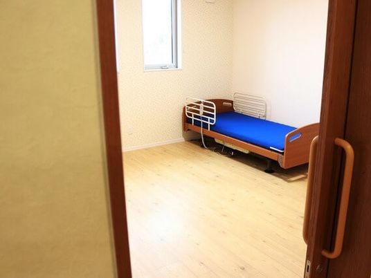 部屋の隅にベッドが置いてある一室を写した写真。引き戸のドアが写っている