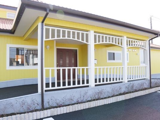 黄色い外壁の明るい雰囲気の建物の玄関には大きな屋根が付き、車の行き来もできる。ゆるやかなスロープも付いている。