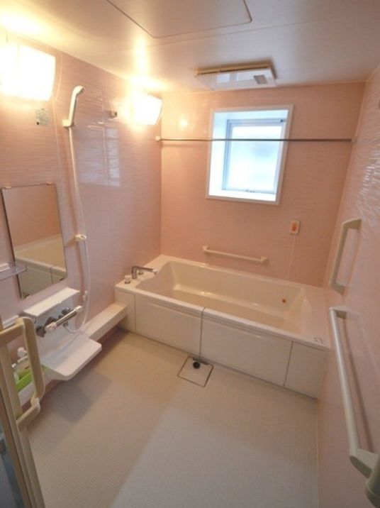 白い浴槽が設置された浴室。シャワーや手すり、鏡なども設置されている。