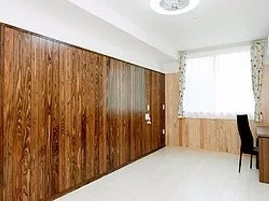 広めの居室内の写真。木目調の壁が印象的な部屋の様子