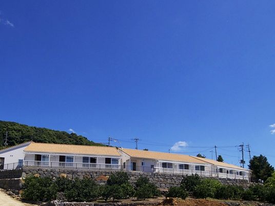 白い壁にオレンジの屋根、自然に囲まれたホームは平屋建て。