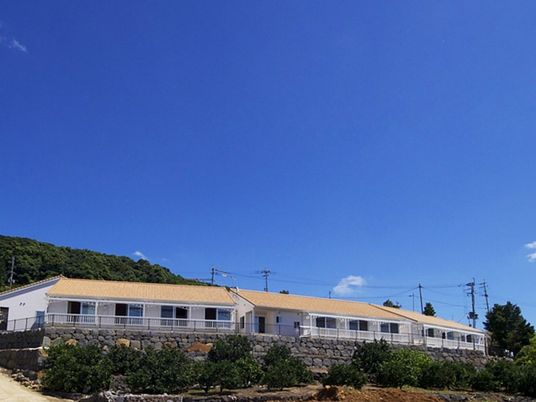 白い壁にオレンジの屋根、自然に囲まれたホームは平屋建て。