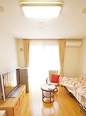 テレビやベッドがある小さなワンルームの部屋の様子。施設内の居室
