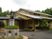 ベージュの外壁の平屋建ての建物にはグレーの瓦屋根が付き、玄関先にはベンチが置かれている。