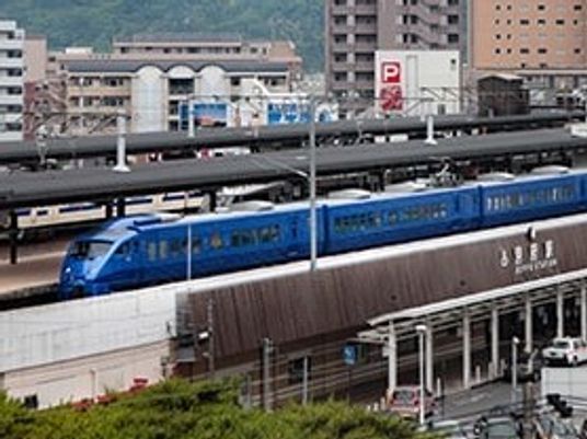 駅周辺のにぎやかな様子。青い電車が止まっている。