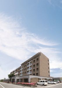 正面に花畑がある茶色い外壁の6階建てケアマンション