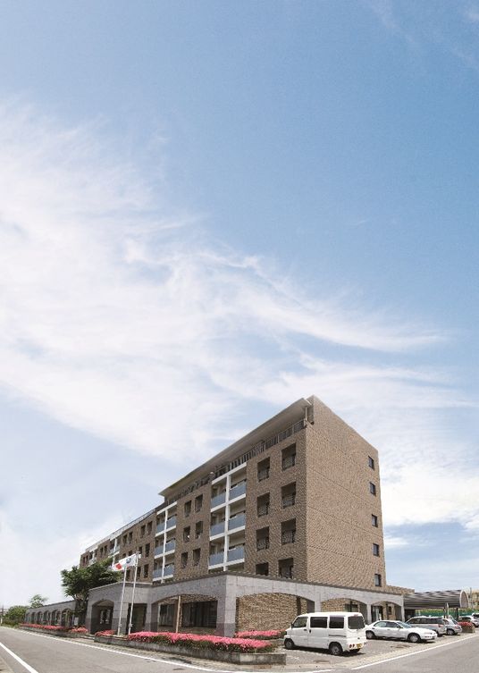 正面に花畑がある茶色い外壁の6階建てケアマンション