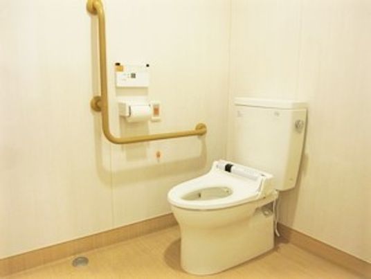 立ち上がり用の手すりが取り付けてある施設内のトイレの写真