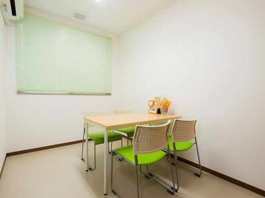 四人掛けのテーブルと椅子がひとつだけ置いてある施設内の相談室の様子