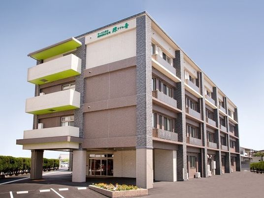 日当たりが良い土地にある建物の外観写真。駐車場がついたマンションのような建物の外観