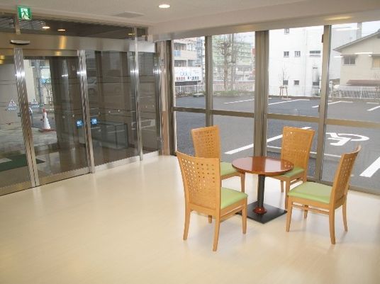 エントランス部分に椅子と机がある様子。外に駐車場