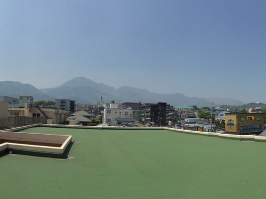 屋上から眺めた景色。遠くに山、手前に街並みがある