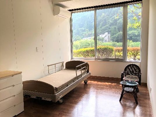 椅子とタンス、一人用のベッドなどが置いてある施設内の居室
