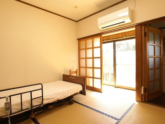 エアコン付きの本格的な和室の部屋には介護ベッドが置かれ、障子もセットされている。