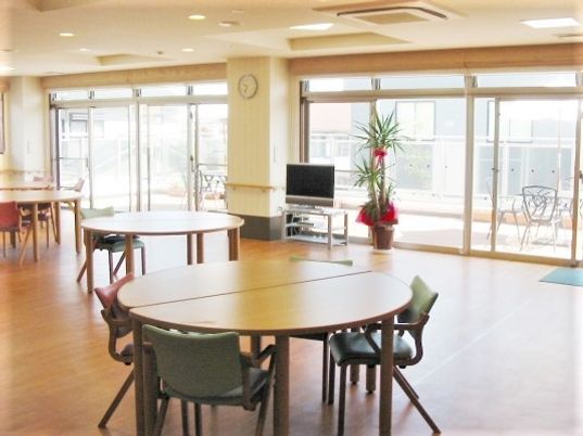 丸テーブルと椅子が数客ずつ並べられている施設の広々としたリビング
