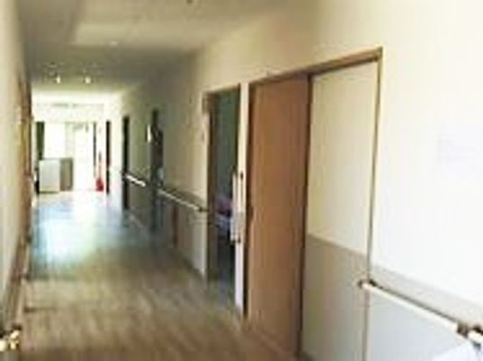 幅の広い廊下の両サイドには居室ドアや手すりが付き、突き当りには共有スペースがある。