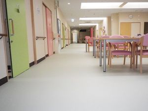オールバリアフリーのゆかがつづく施設内のリビング。左側に居室のドア、右側にリビングルーム