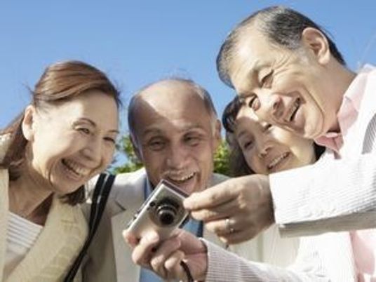 ご高齢の男女４名がカメラの写真を見ながら微笑んでいる様子。