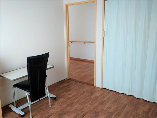 施設内の一室にイスとテーブルが置いてある共有スペースの様子