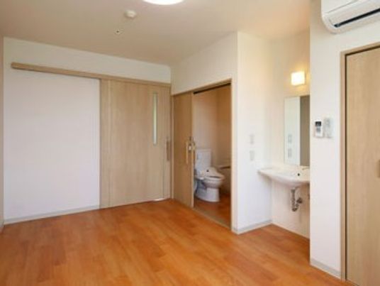 トイレと洗面所が付いたフローリングの居室には、照明やエアコンもあり、ドアは引き戸。