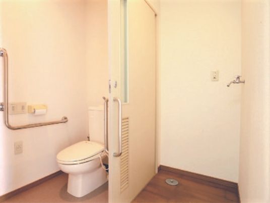 L字型の手すりがついた広めのトイレと洗濯機置き場の様子。居室内設備