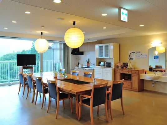 食堂には食器棚やキッチン、洗面所が付き、ダイイングテーブルが置かれ、大きな窓のそばにはテレビも設置されている。