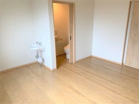 フローリングの部屋には車いす対応の洗面所やスライド式のドアが付いた広いトイレがあり、家具は置かれていない。
