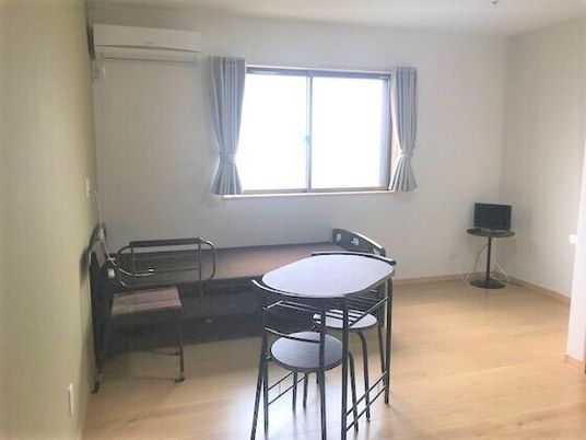 大きな窓にはカーテンが付き、寝具付きのベッドが置かれ、テーブルセットやテレビ、エアコンもついている。